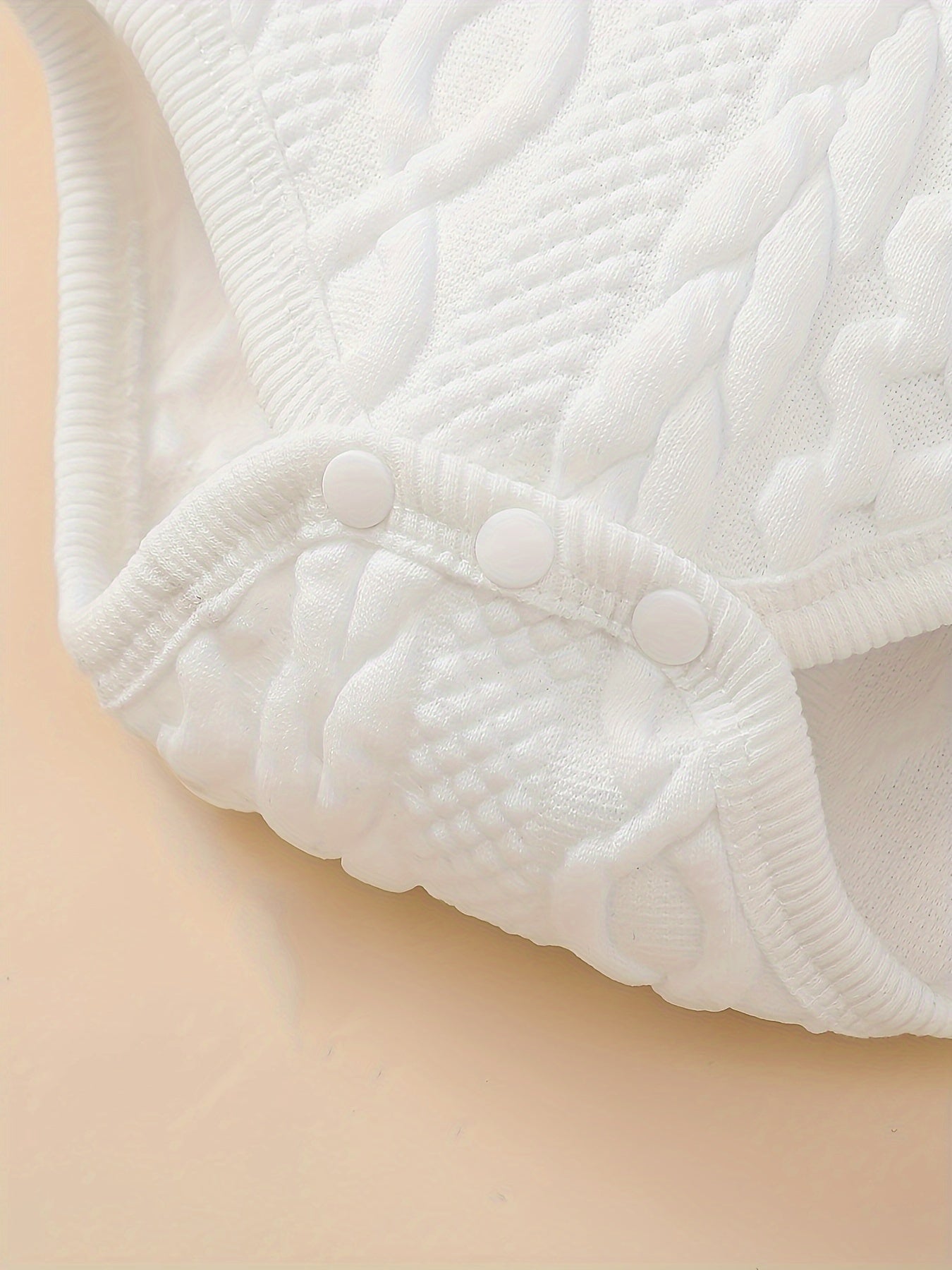 Close-up of a textured white fabric with buttons on a beige background