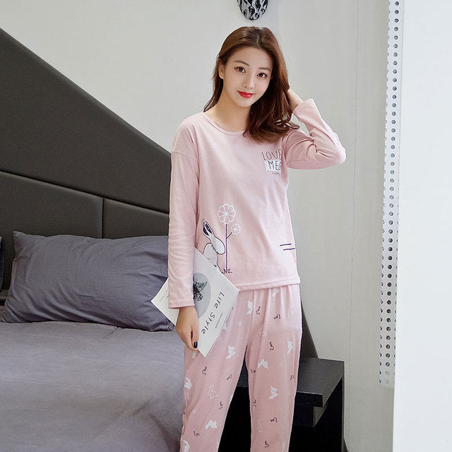 Woman wearing pink pajamas with a white dog design in a bedroom setting.