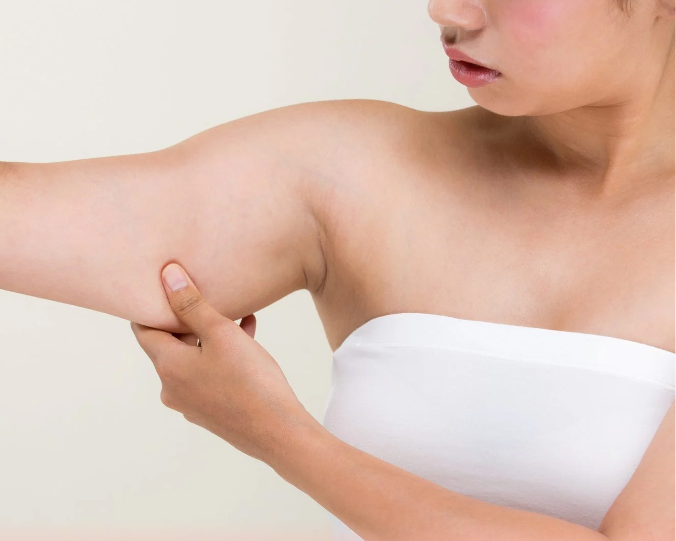 Woman holding arm with text about skin firming and lifting effect on a light background