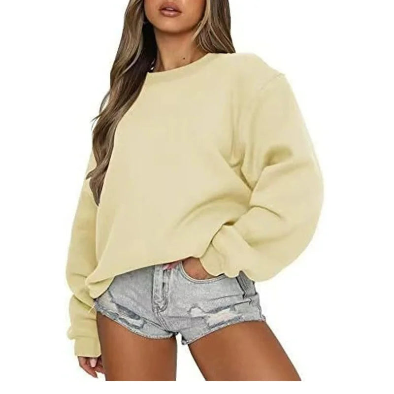 Woman wearing a light yellow oversized sweater and denim shorts on a white background