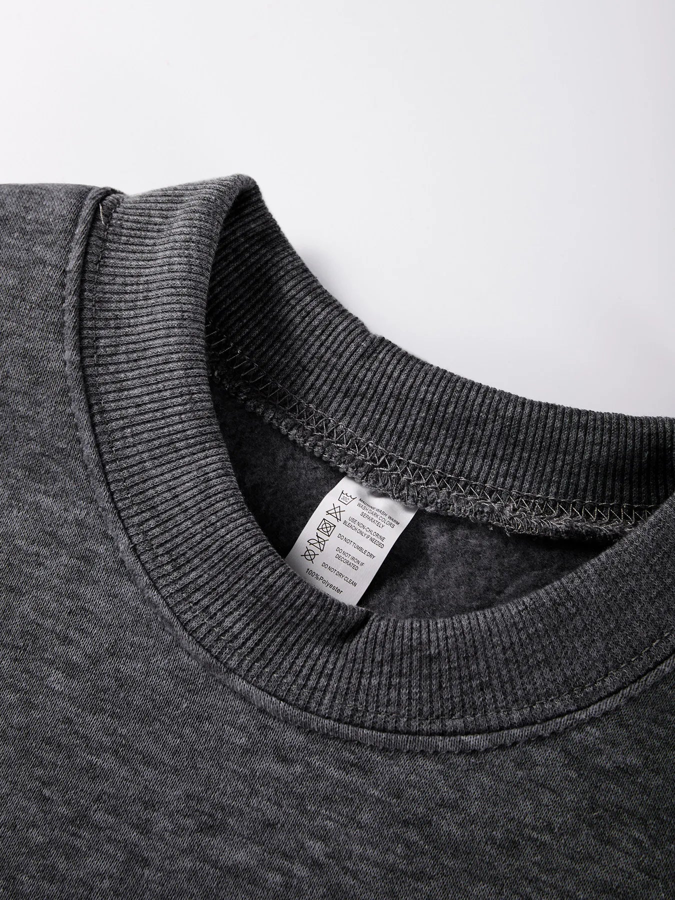 Close-up of a gray sweatshirt collar with a label on a white background