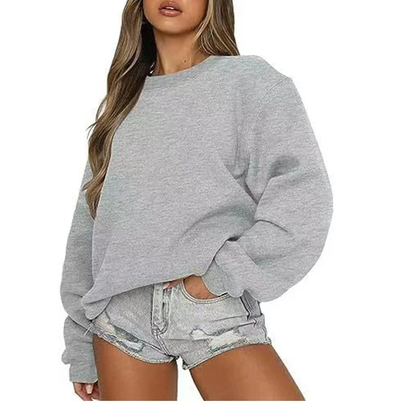 Person wearing a gray sweatshirt and denim shorts on a white background