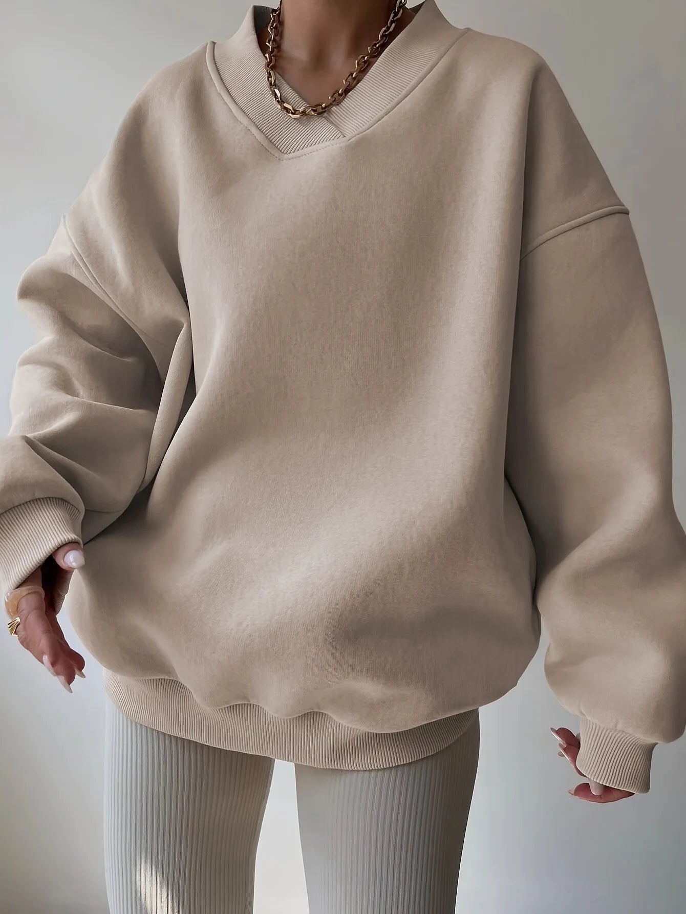 Beige oversized sweater worn by a person on a plain background