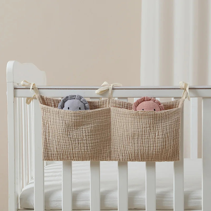 Beige fabric storage baskets hanging on a crib with plush toys inside.