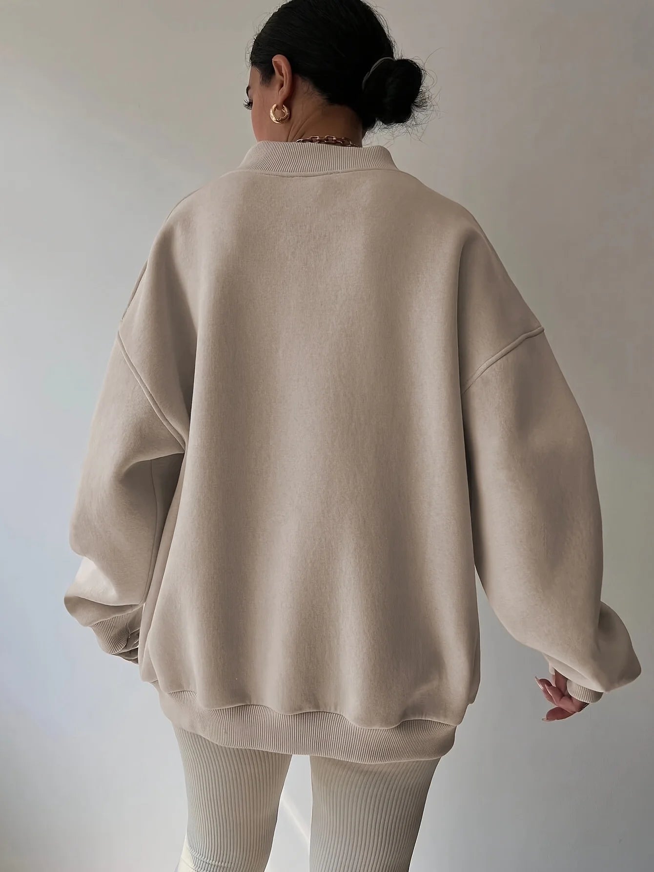 Person wearing a beige oversized sweater and pants against a plain background