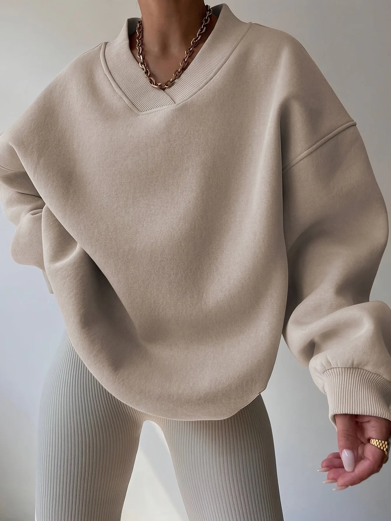Beige sweater worn by a person on a plain background